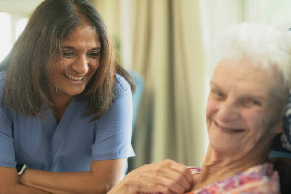 A warm, inviting assisted living community with seniors smiling and engaging in activities in a cozy common area